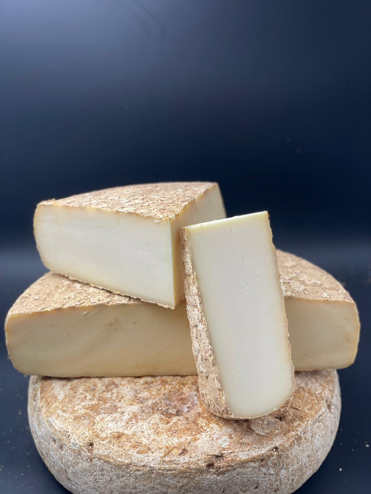 Dentella – Tomme de brebis, fromage affiné de 6 mois, en gros plan sur une surface en pierre montrant sa texture fondante et son apparence artisanale.