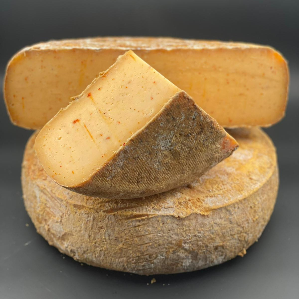 Gros plan sur le fromage Far Aqui Piment d'espelette, tranche de 375g de tomme de brebis artisanale au piment d'Espelette.