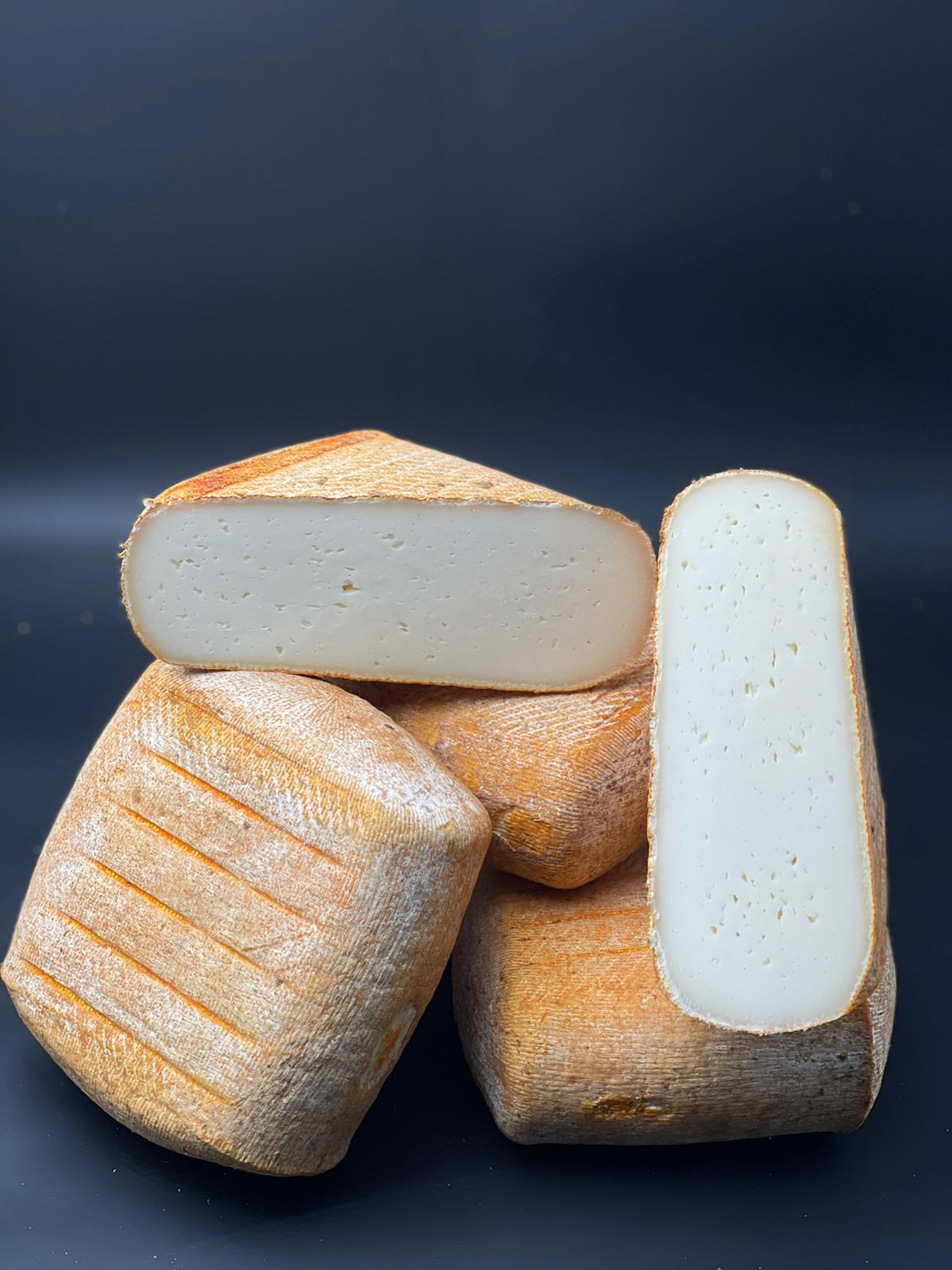 Pavé du Larzac brebis empilé, fromage affiné de brebis, présenté sur une surface noire, illustrant sa texture rustique et artisanale.