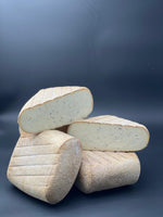 Pavé du Larzac Truffé empilé, montrant une texture crémeuse avec des éclats noirs visibles, soulignant ses saveurs truffées distinctives.