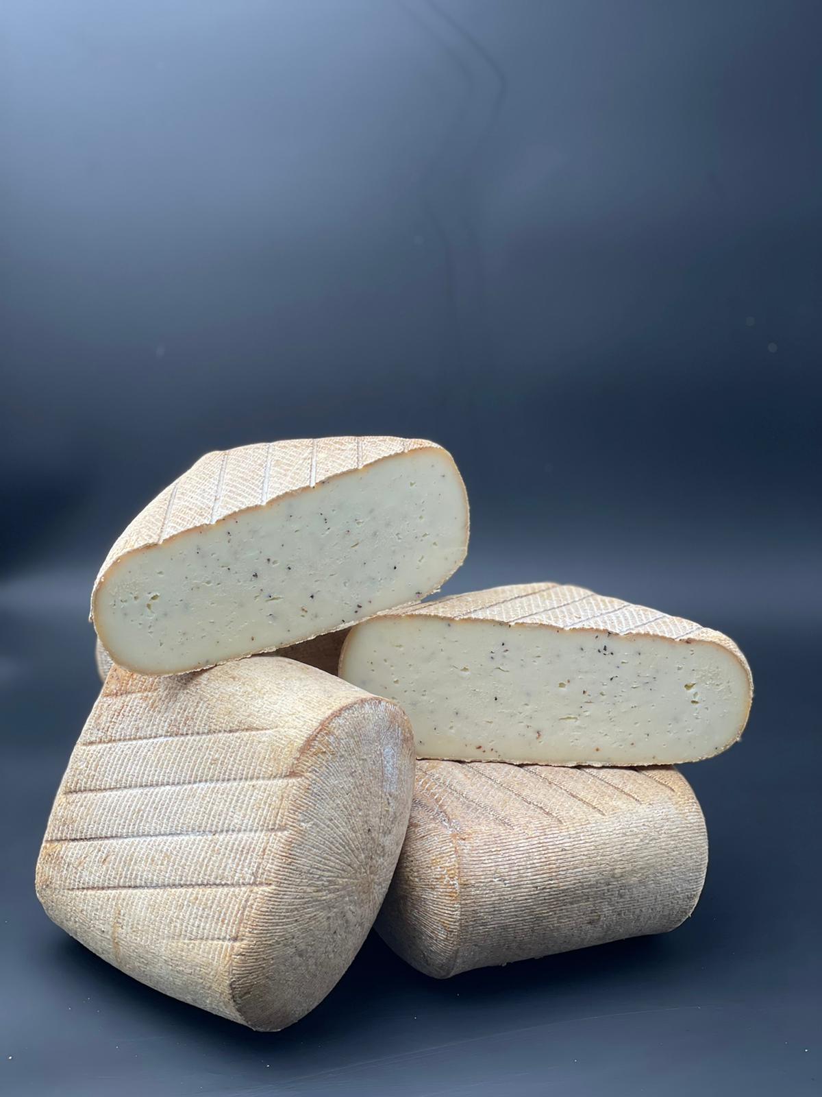 Pavé du Larzac Truffé empilé, montrant une texture crémeuse avec des éclats noirs visibles, soulignant ses saveurs truffées distinctives.