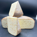 Tomme de brebis Far Aqui Fenu Grec, empilée, mettant en valeur une tranche de 450g sur une surface sombre, avec un goût de noix.