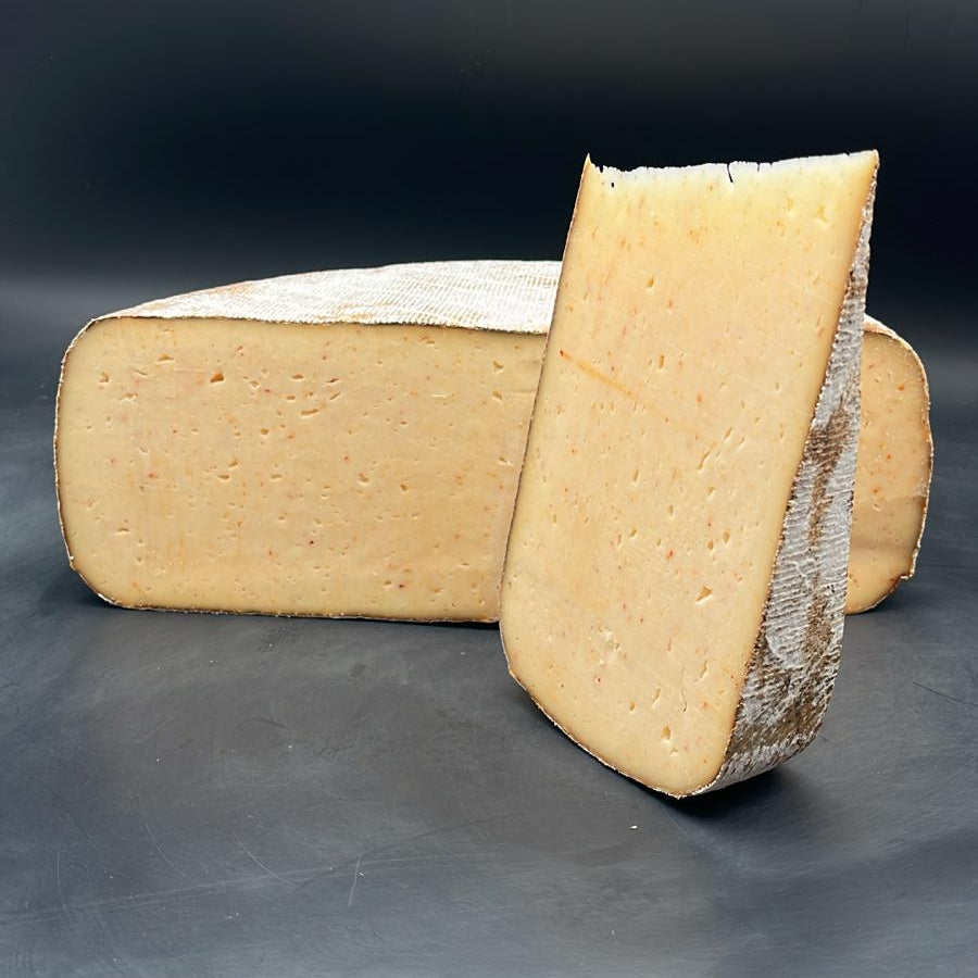 Tomme de brebis artisanale Far Aqui Piment d'Espelette, bloc de 375g, sur une table, illustrant sa texture robuste.