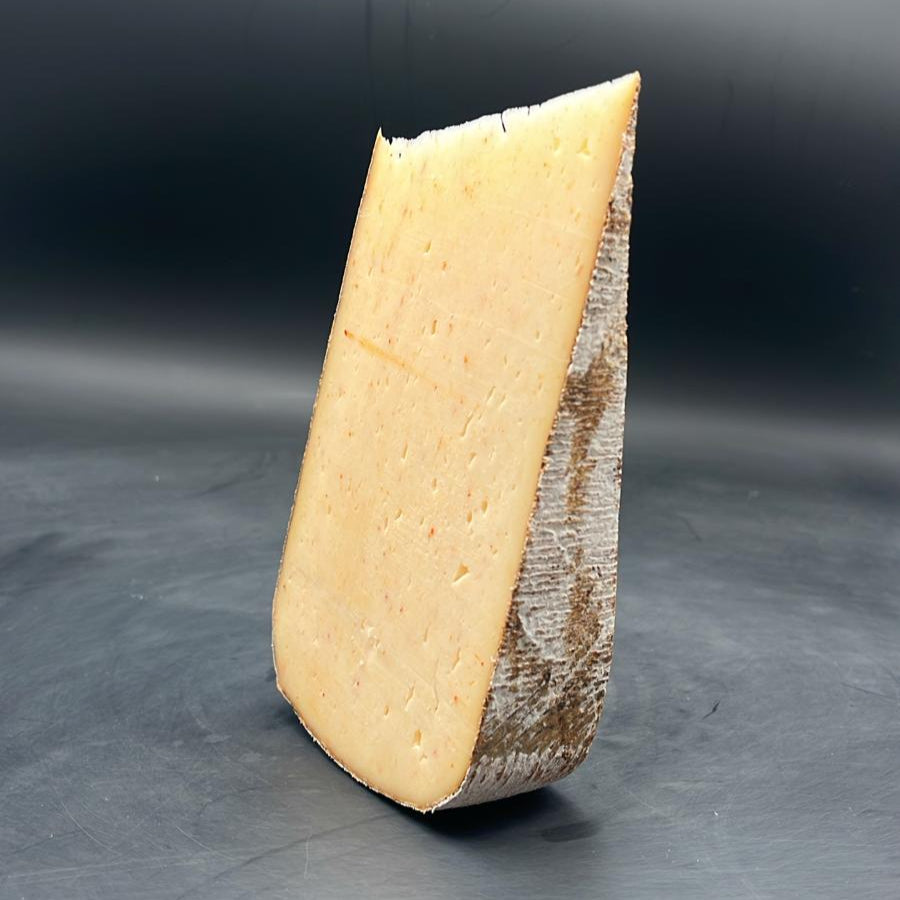 Tomme Far Aqui Piment d'Espelette sur surface grise, morceau de 375g. Fromage artisanal au lait de brebis thermisé, goût intense.